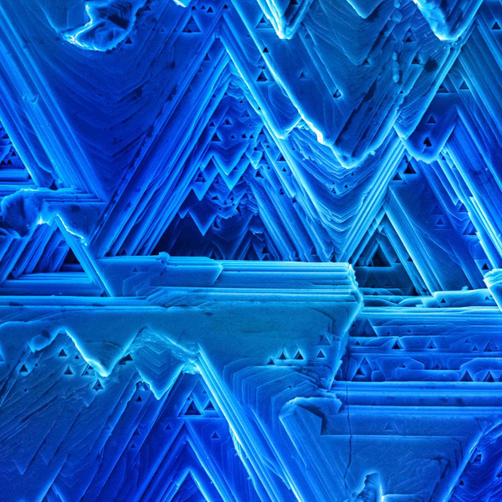 En esta micrografía observamos diferentes microestructuras cristalinas formadas durante la síntesis de un material semiconductor de cobre. La manera como se van apilando las capas cristalinas para formar este material nos recuerda la forma como se crean los glaciares. 